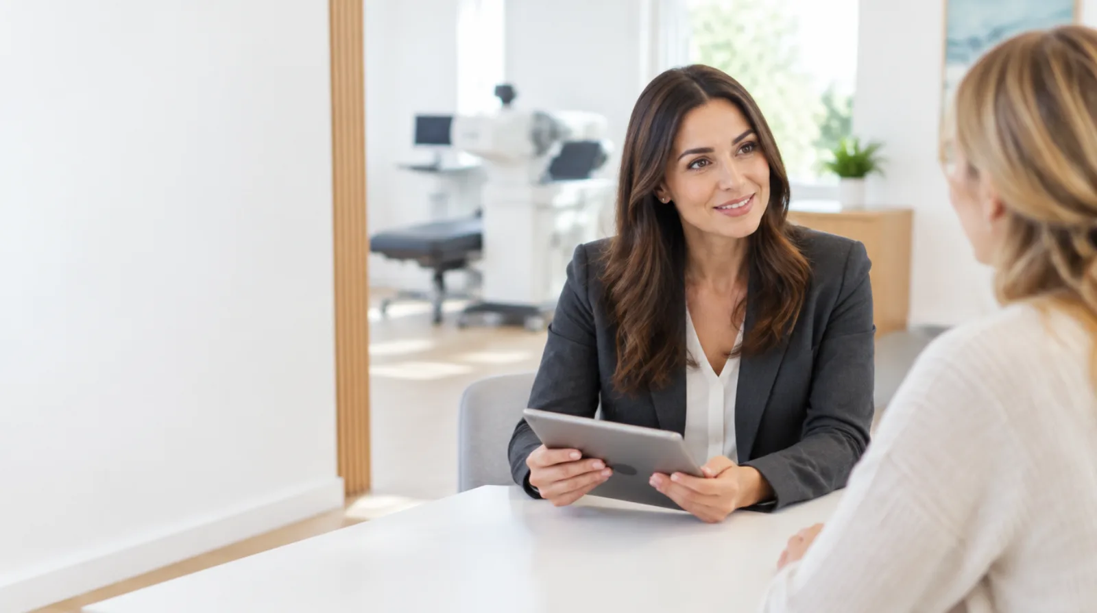 Refractive surgery coordinator consulting with a LASIK patient at a white table